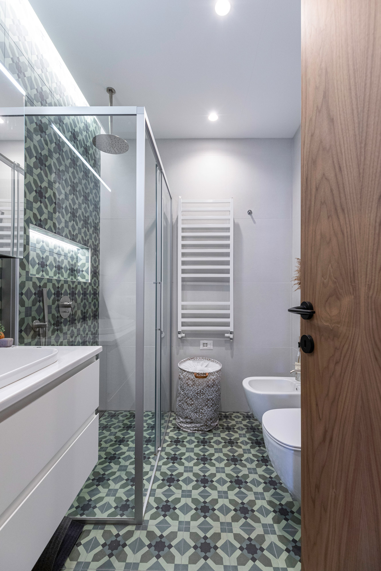 Bagno_verde scuro Bagno elegante in verde scuro, con mattonelle geometriche e doccia in cristallo.